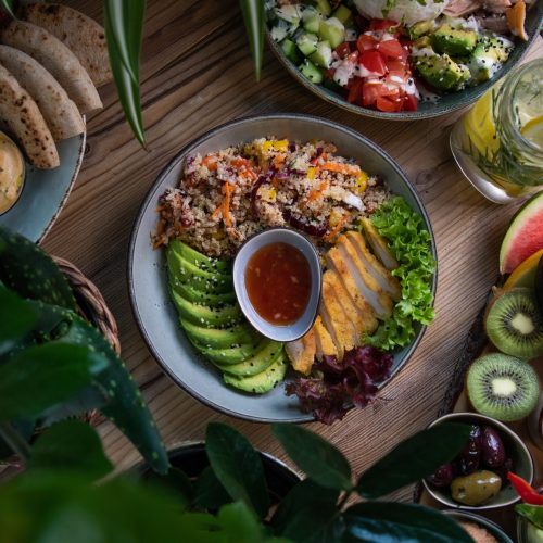 A high angle shot of plates of salad and fresh fruits and vegetable on a wooden surface